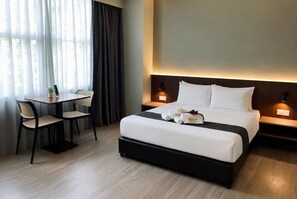 A hotel room with a bed, bedside tables, a desk with a chair, and a window with curtains. - Roxy Hotel Aiman (Kota Samarahan)