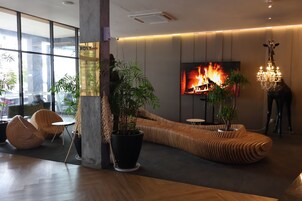 Un interior moderno con un televisor grande mostrando una chimenea, un sofá curvo único y una araña.