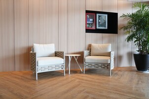 A modern room with two white cushioned chairs, a small round table, and a potted plant.
