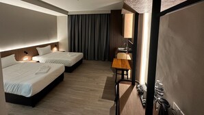 Habitación de hotel con dos camas, un escritorio pequeño, un espejo y un minibar.