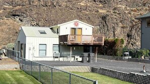 A two-story building with a balcony, a fenced yard, and a rocky hillside in the background. - *Sunland Estates* Stunning property (Quincy)