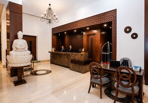 A reception area with a statue, a reception desk, and a seating area with chairs. - Bel-La Monde Hotel NH8 at 6km from IGI Airport Delhi (New Delhi)