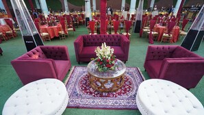 A formal event space with red and white furniture, including sofas and ottomans, arranged around a central table with a floral arrangement.