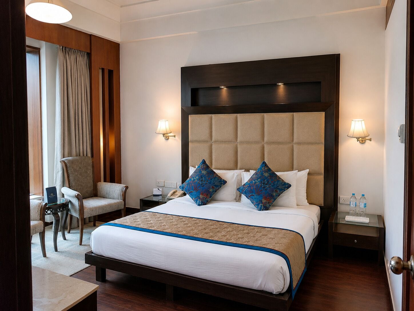 Een hotelkamer met een groot bed, twee nachtkastjes, een stoel en een bureau.
