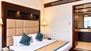A hotel room with a large bed, a bedside table with a lamp, and a view of the bathroom.