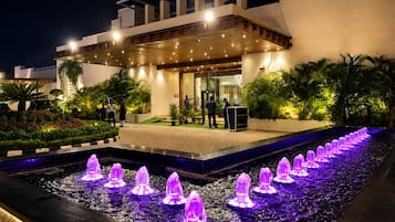 Entrada de hotel con fuente de agua y zona exterior cubierta.