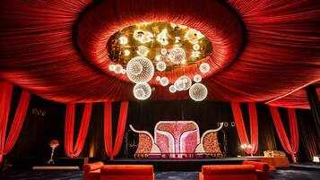 A theater with red curtains, a stage with a red and white backdrop, and a chandelier.