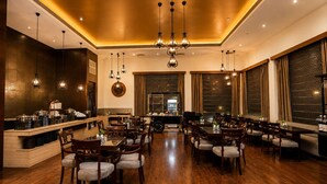 A spacious dining area with wooden flooring, multiple dining tables, and chairs. - Bel-La Monde Hotel NH8 at 6km from IGI Airport Delhi (New Delhi)