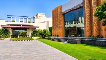 A modern building with a large glass facade, a well-maintained lawn, and a clear sky.