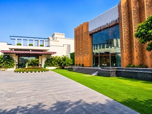 A modern building with a large glass facade, a well-maintained lawn, and a clear sky.