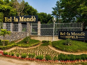 Señal para Bel-la Mondè Hotels, con un muro de piedra y una puerta de metal.