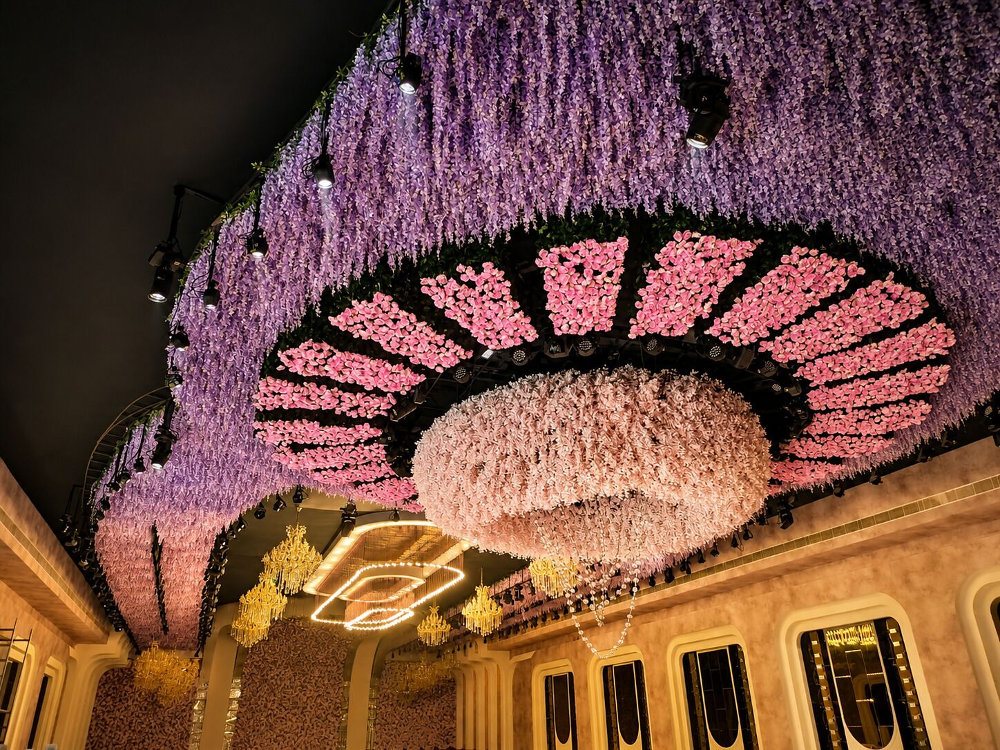 A ceiling with floral arrangements and chandeliers.