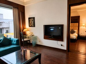 Una habitación de hotel con televisión, escritorio con lámpara, sofá y cama.
