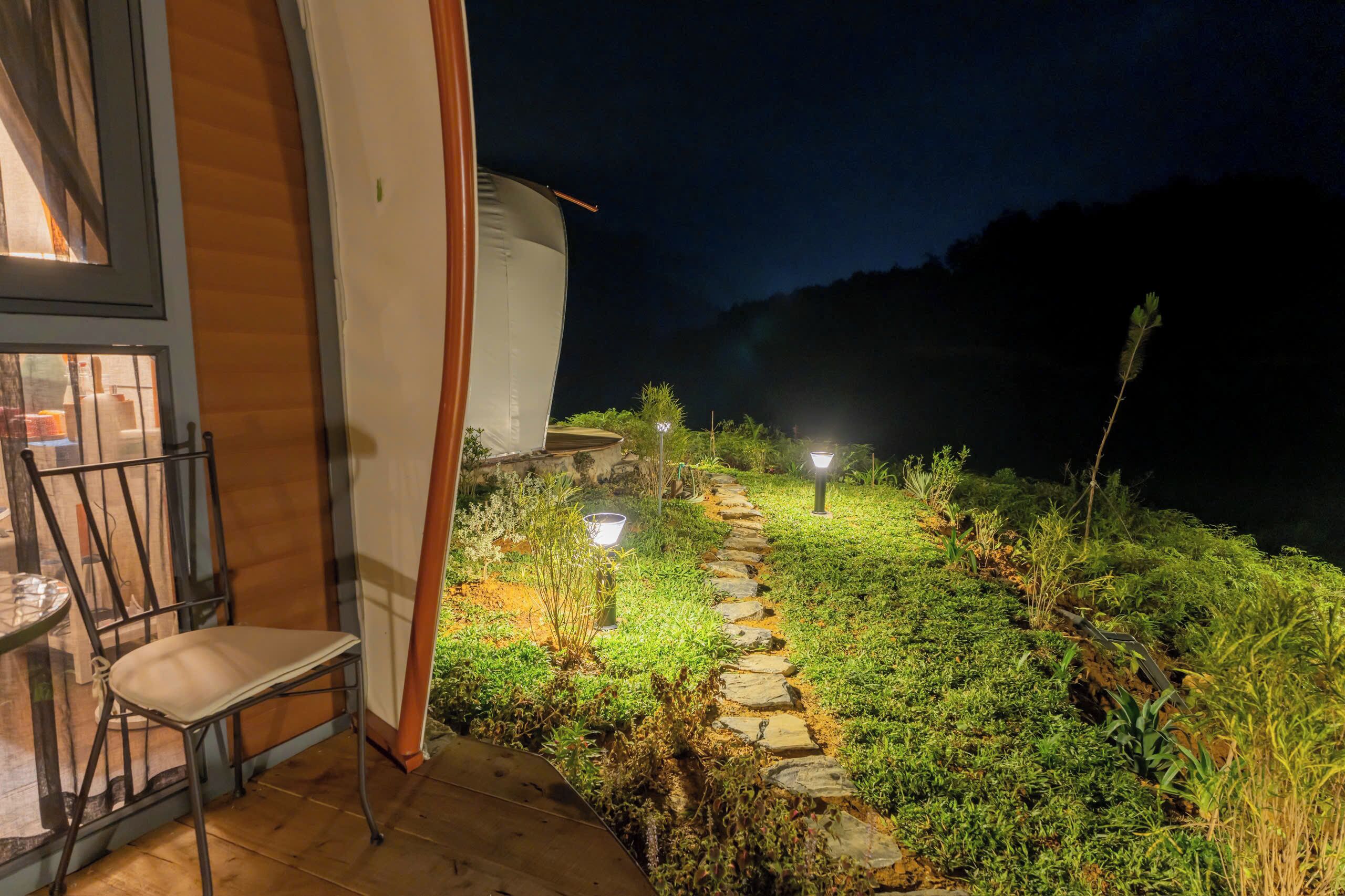 Un patio con una silla, un sendero de piedra y un edificio con puerta de vidrio.