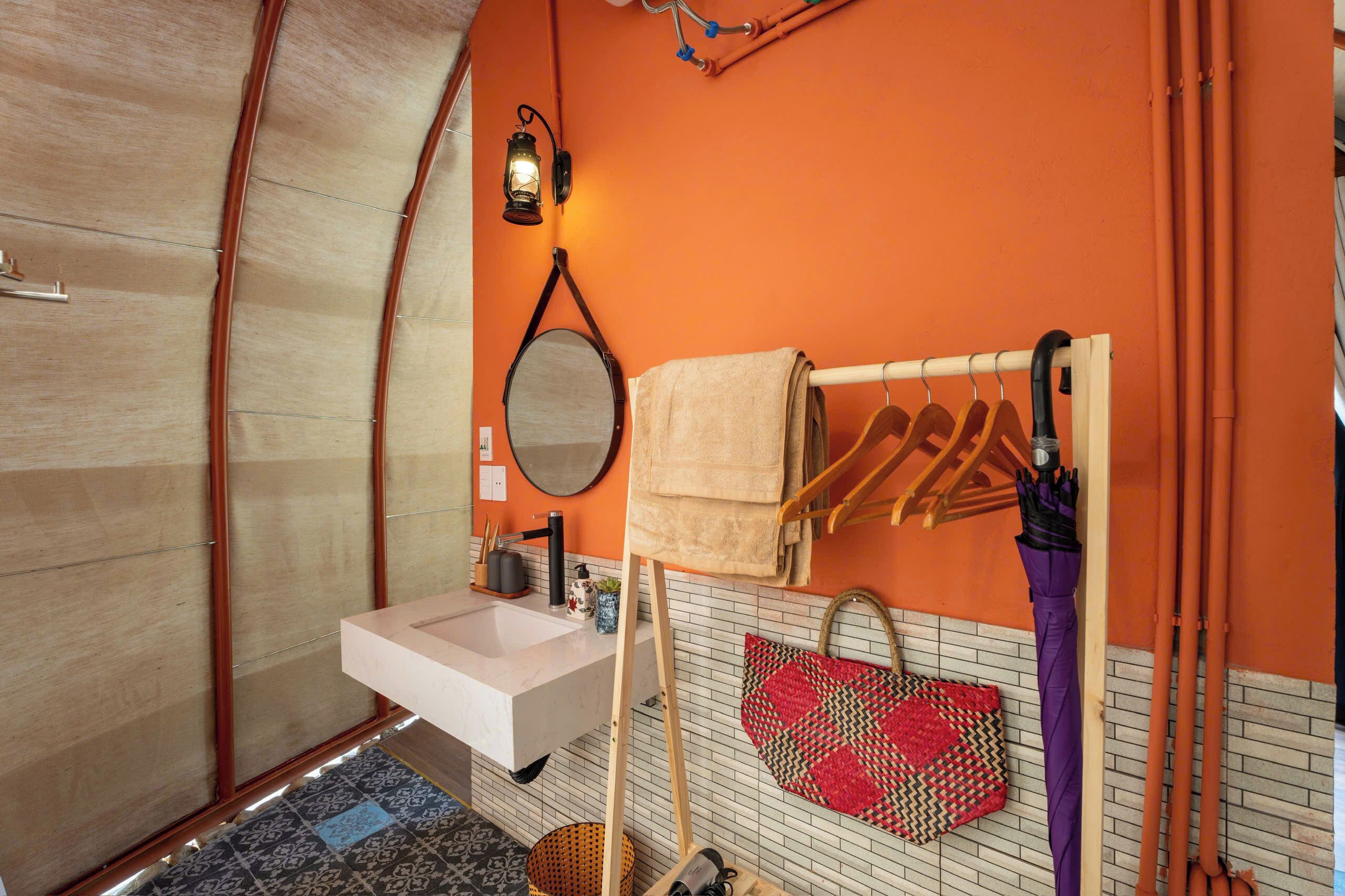 A bathroom with a white sink, a mirror, a towel rack, and a hanging bag.