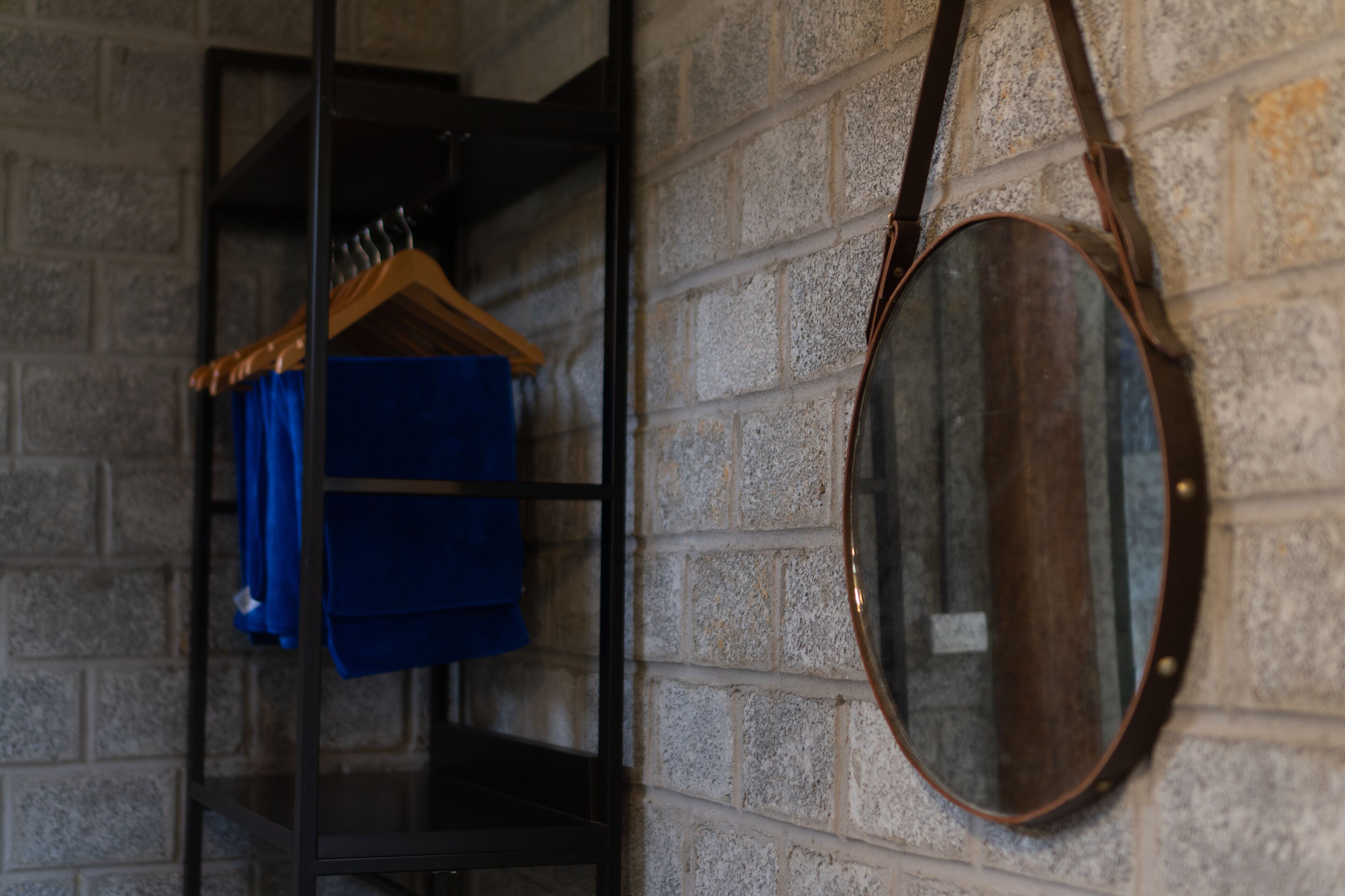 A room with a brick wall, a wooden hanger, and a mirror.