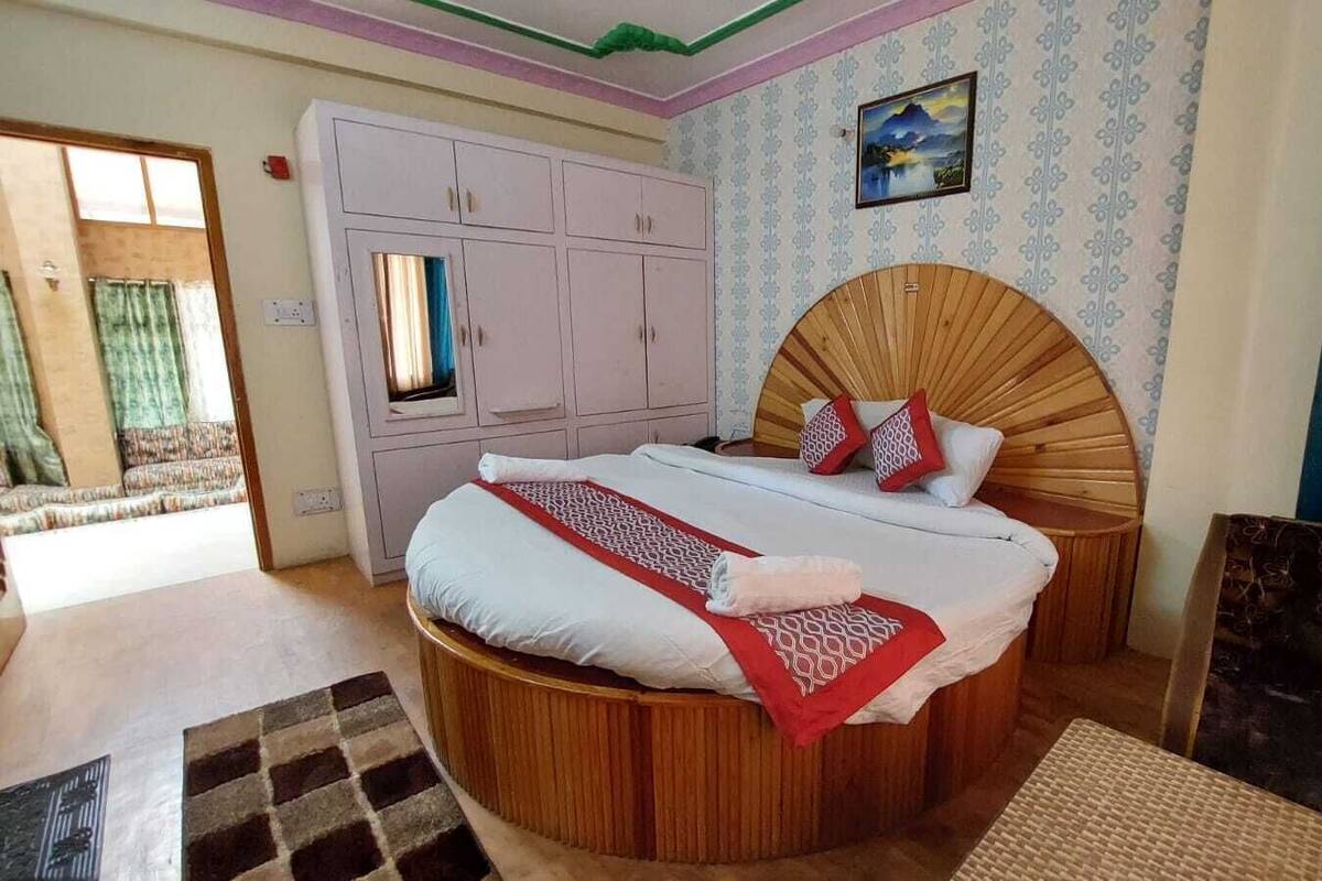 Un dormitorio con una cama redonda de madera, un armario y vistas al exterior.