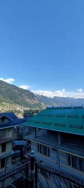 Vista di un paesaggio montuoso con un edificio dal tetto verde in primo piano.