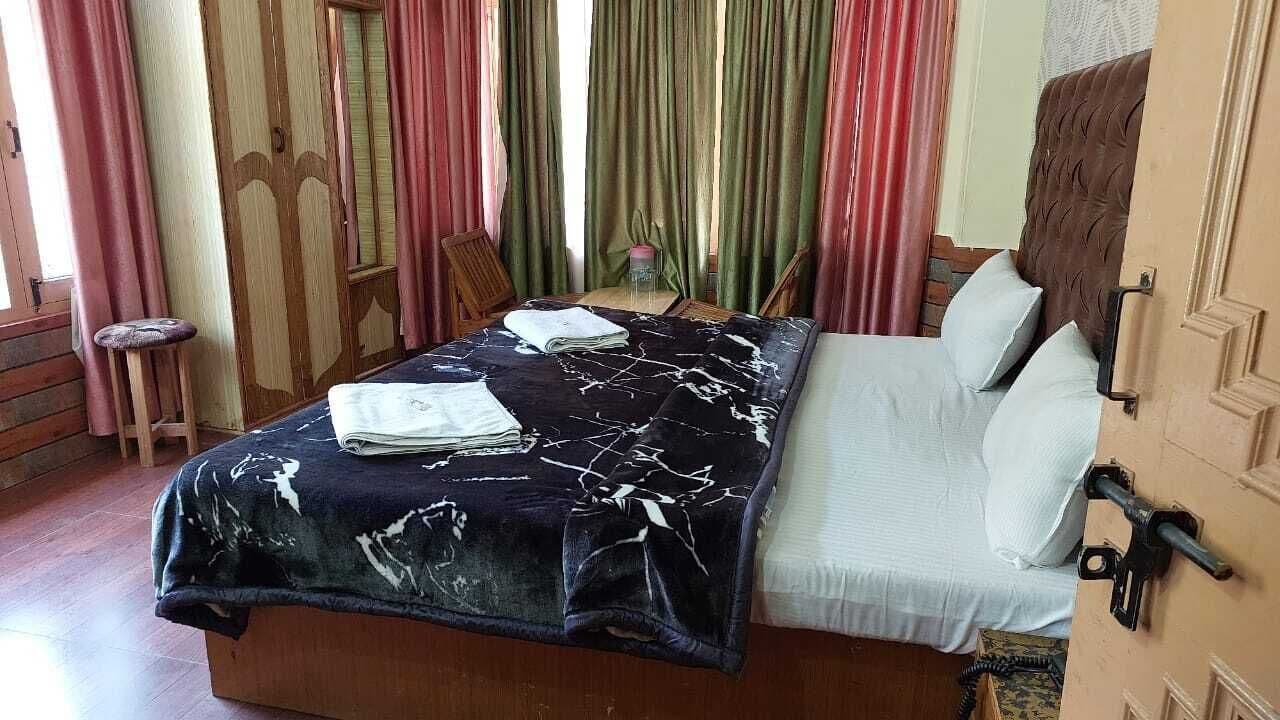 Un lit avec une couvre-lit à motifs noir et blanc, une tête de lit en bois et des oreillers blancs.