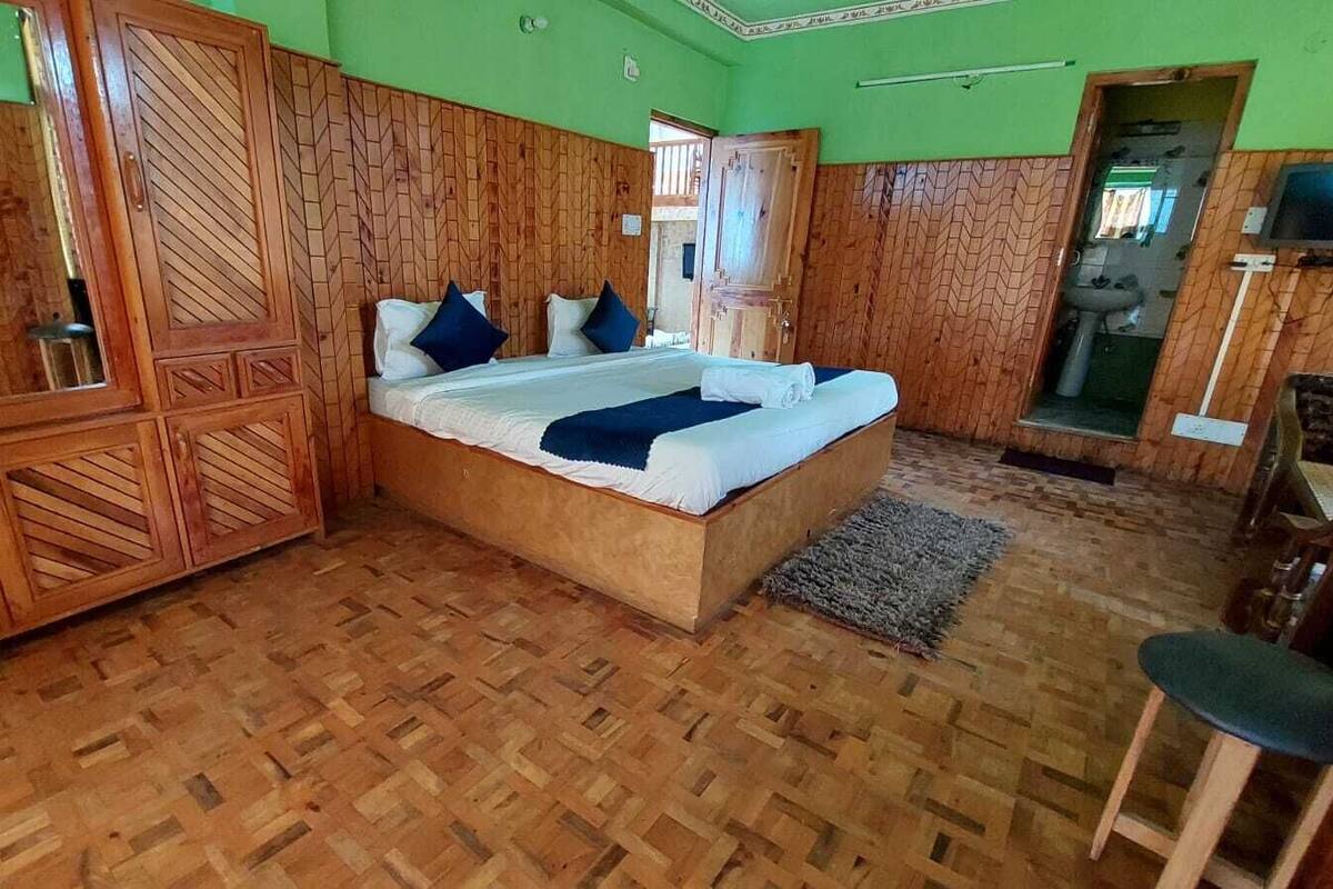 Una habitación con paneles de madera, una cama, una pequeña mesa y un televisor.