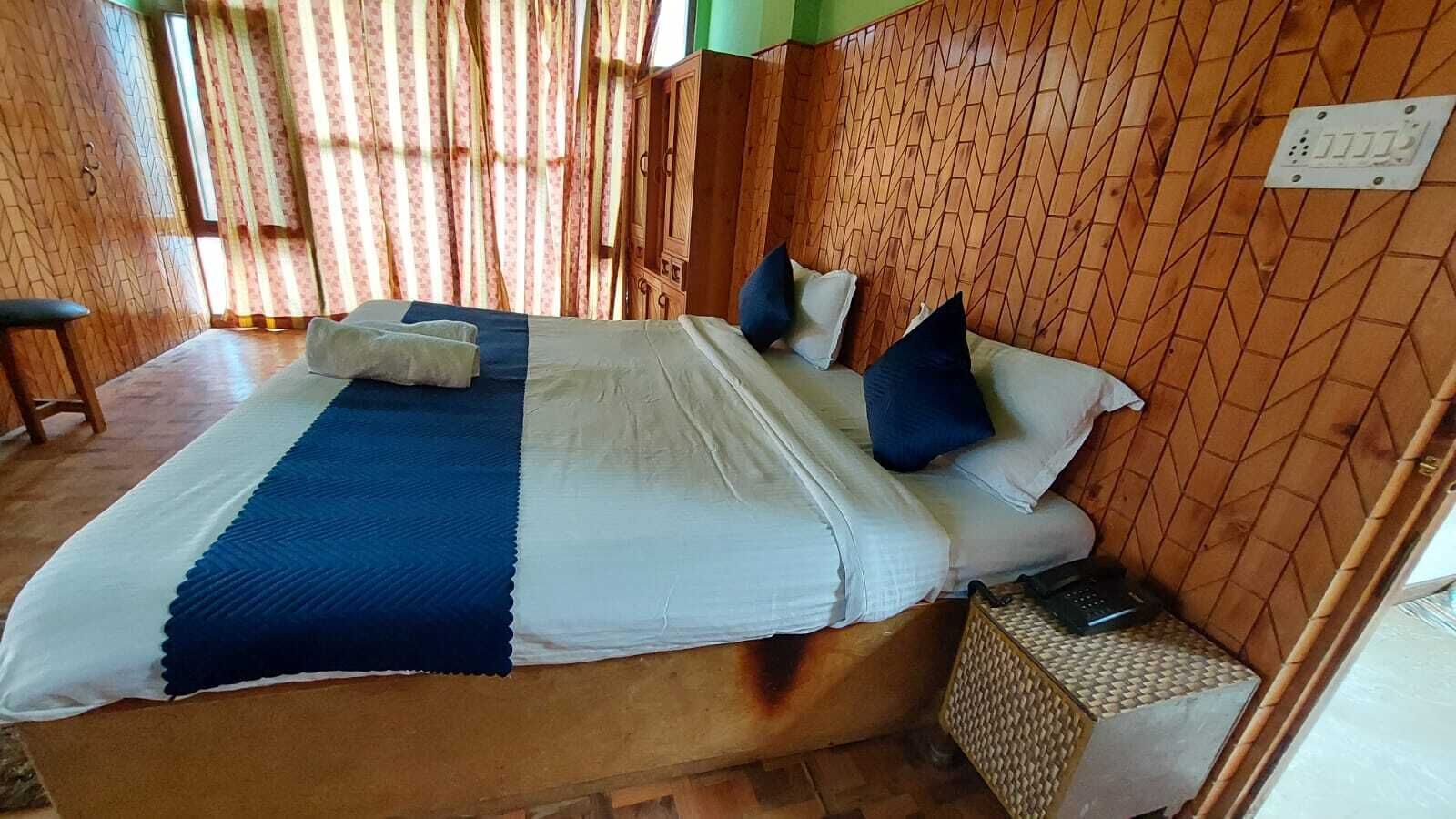 Ein Bett mit blauer und weißer Bettdecke, zwei Kissen und ein Nachttisch mit einer Lampe.