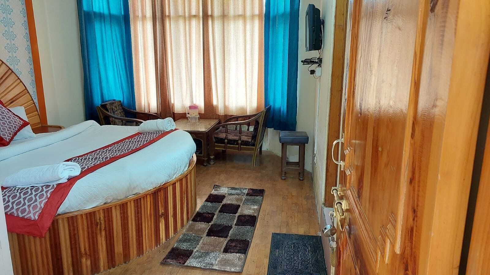 A bedroom with a bed, a small table, a chair, and a wooden door.