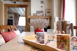 Een eettafel met een dienblad, twee mokken, een glas en een zilveren pot.