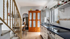 A kitchen with a wooden staircase, white cabinets, and a tiled floor. - Holiday Home "Calle Ancha" with Private Terrace & Wi-Fi (Barbate)