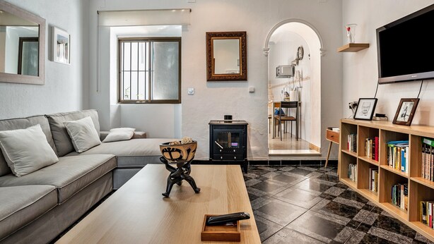 A modern living room with a sofa, a coffee table, a bookshelf, a fireplace, and a television. - Holiday Home "Calle Ancha" with Private Terrace & Wi-Fi (Barbate)