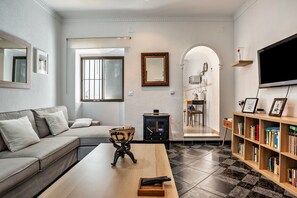 A modern living room with a sofa, a coffee table, a bookshelf, a fireplace, and a television.