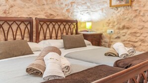 Ein Schlafzimmer mit zwei Betten, Holz-Kopfteilen und einer Steinwand.