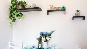 Ein Essbereich mit einem Tisch für zwei Personen, einer Blumenvase und zwei Wandregalen mit Dekoration.