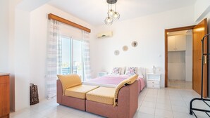 Ein Schlafzimmer mit Bett, Schlafsofa, Nachttisch, Lampe, Kleiderschrank und einem Fenster mit Vorhängen.