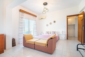 Une chambre à coucher comprenant un lit, un canapé-lit, une table de chevet, une lampe, une armoire et une fenêtre avec des rideaux.
