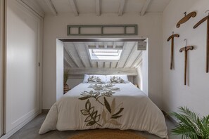 A bedroom with a bed, a skylight, wooden hangers, and a plant. - Holiday Apartment 'Il Nido' with Air Conditioning and Wi-Fi (Buonconvento)
