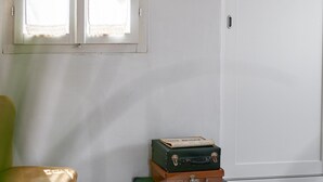Una habitación con una silla, maletas apiladas, una puerta y una ventana.
