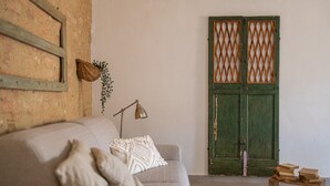 Una habitación con sofá, lámpara, mesa de madera y puerta verde.
