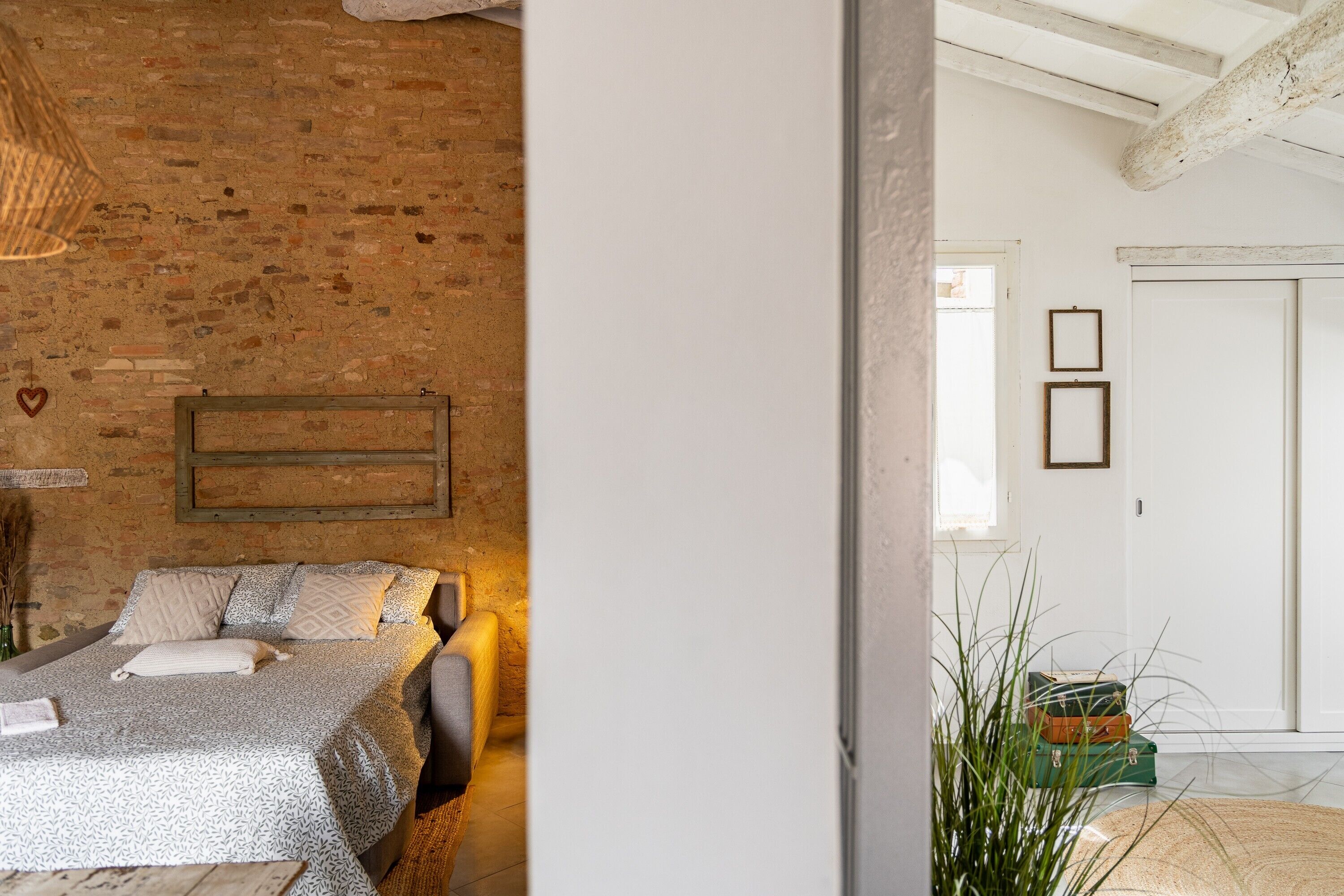 Ein Zimmer mit einem Bett, einer Ziegelwand, einer Holzbalkendecke und einer Tür mit eingekachelten Bildern.