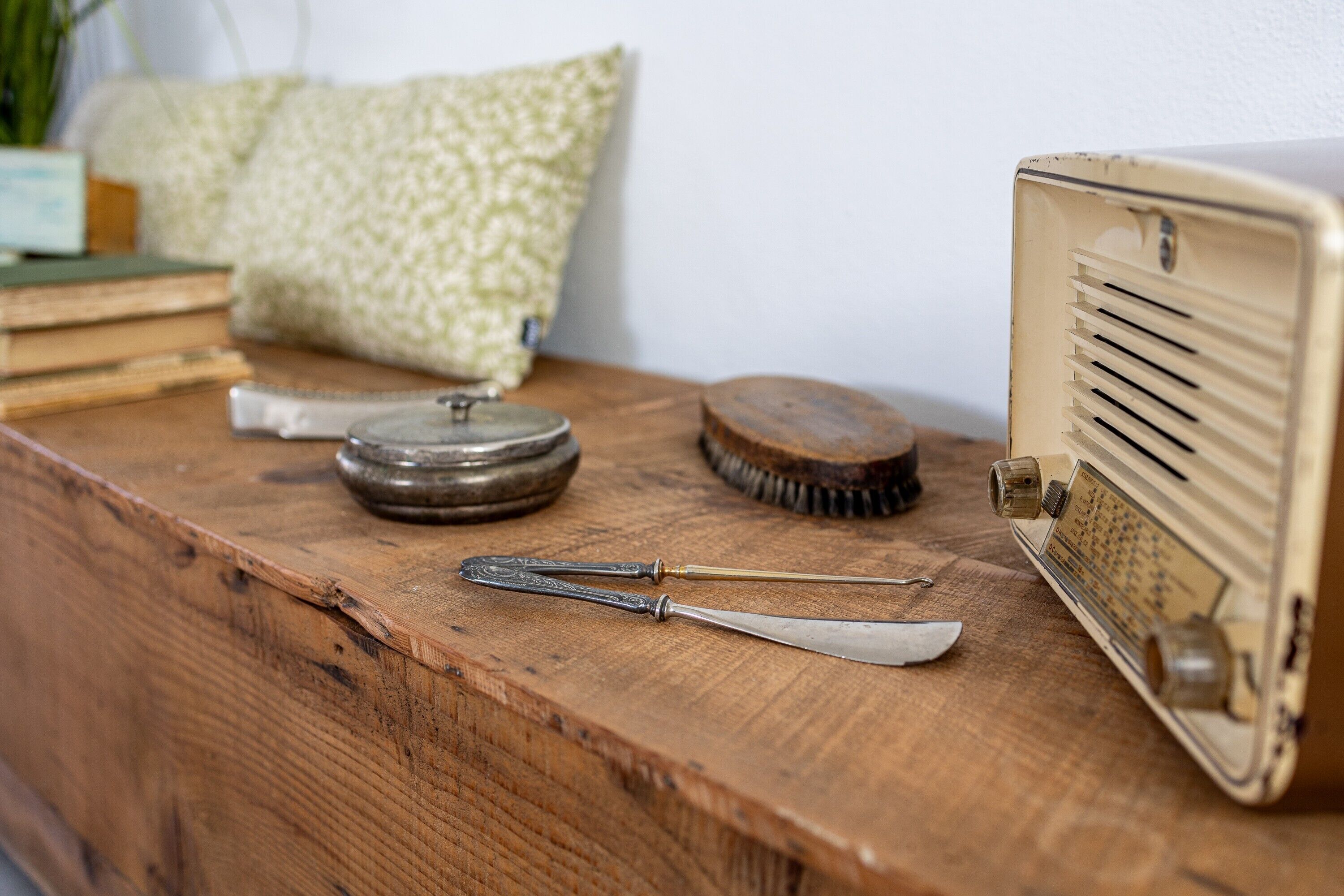 Een oude radio, een vergrootglas, een kwast en een boek op een houten oppervlak.