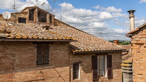 Un edificio tradicional de ladrillo con tejado de baldosas, múltiples antenas y una chimenea.