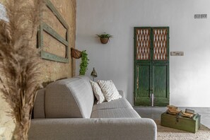 A room with a sofa, a green door, a small plant, and a stack of books on a table. - Holiday Apartment 'Il Nido' with Air Conditioning and Wi-Fi (Buonconvento)