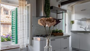 Una cocina con ventana, un jarrón con flores y una mesa con una cesta.