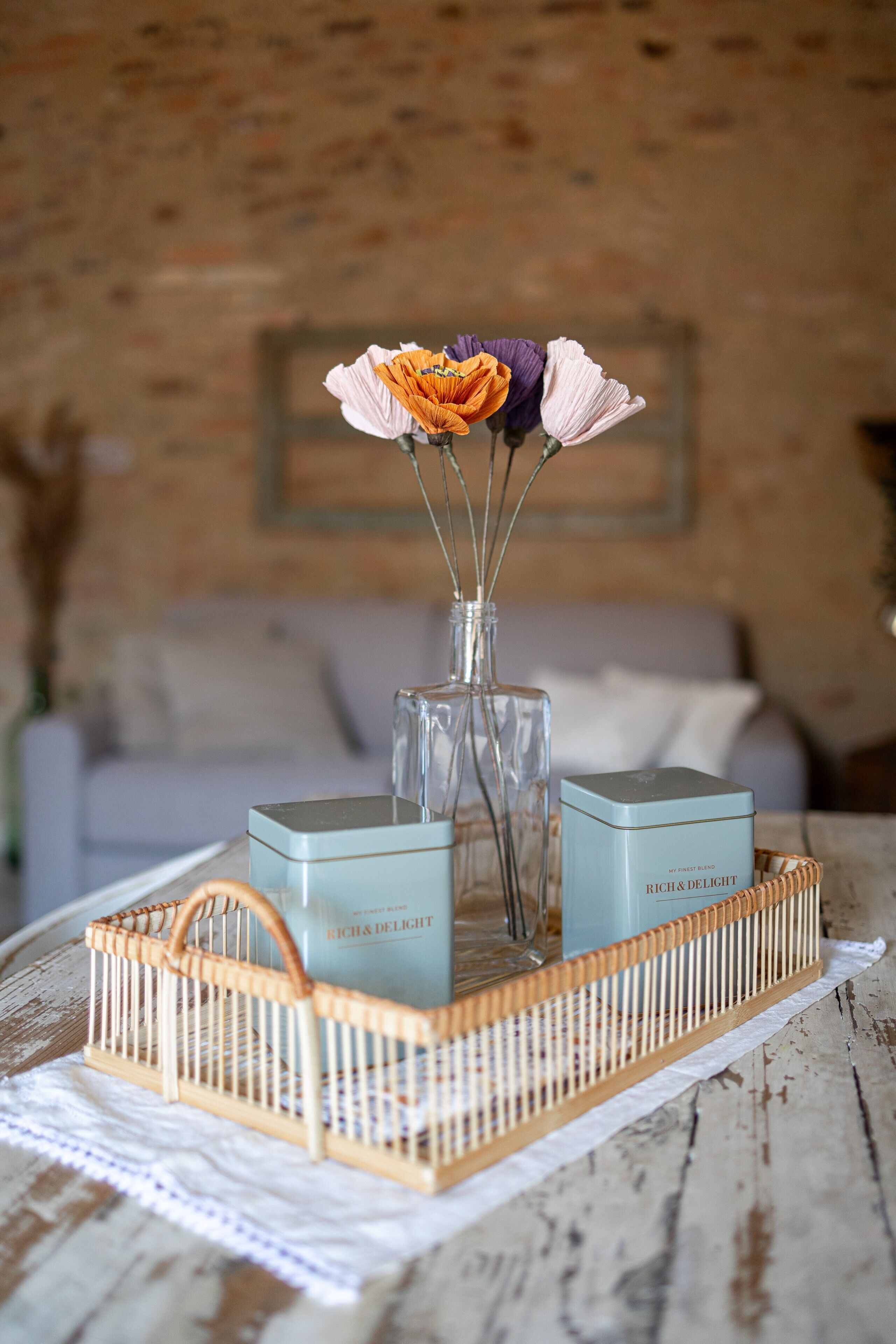 Un plateau sur lequel se trouvent un vase de fleurs et deux récipients rectangulaires, le tout posé sur une surface en bois.