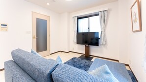 A living room with a sofa set, a flat-screen TV, and a window with curtains. - Minamiaoyama 1st (Tokyo)