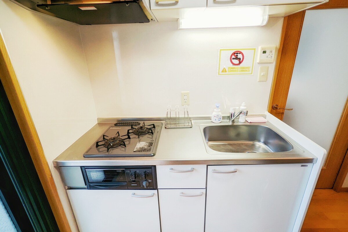 Une petite cuisine équipée d’une cuisinière à gaz, d’un évier et d’un lave-vaisselle.