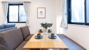 A dining table with four blue cups and saucers, a vase with flowers, and a framed picture on the wall. - Minamiaoyama 1st (Tokyo)