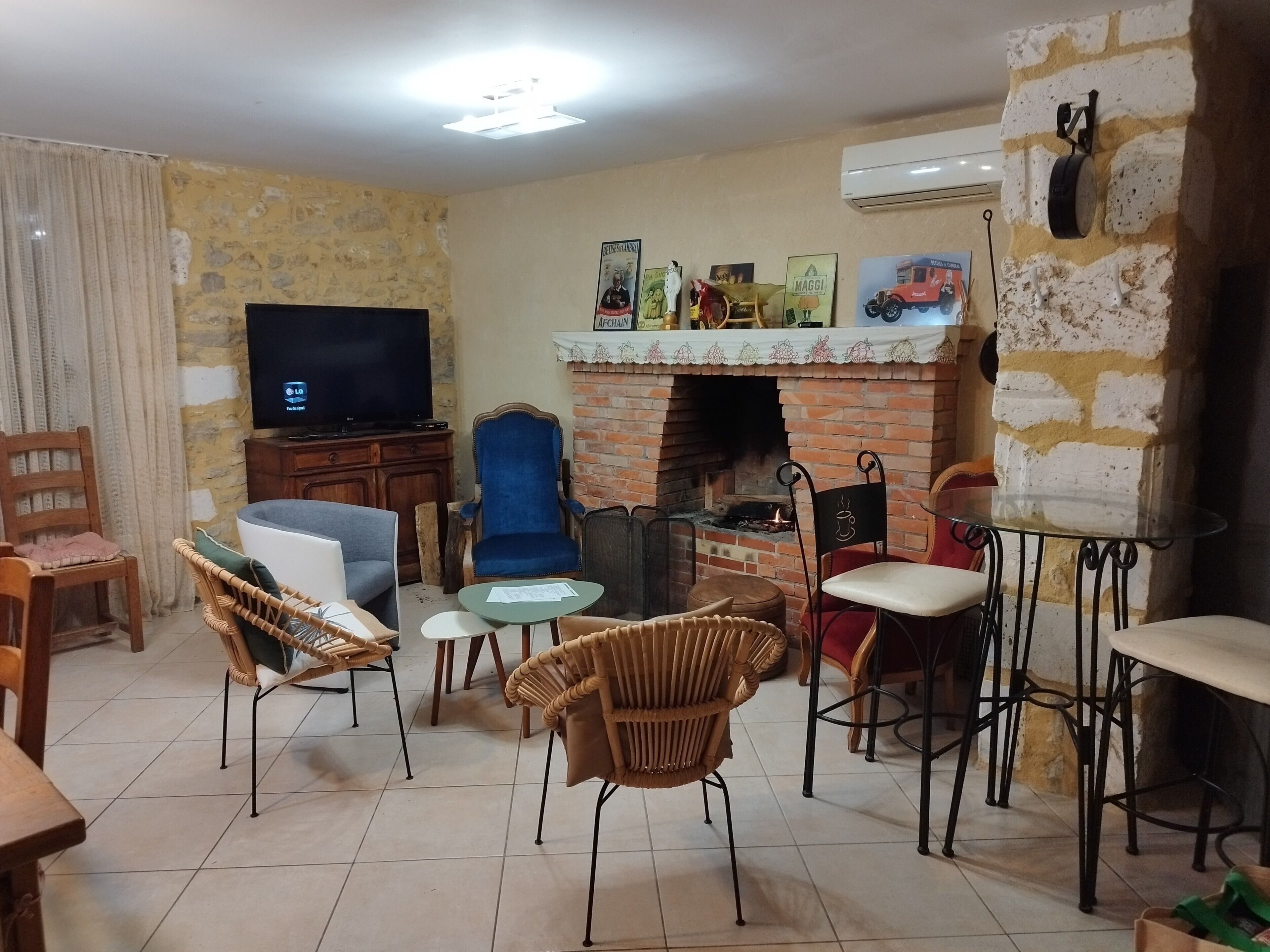 A living room with a TV, fireplace, wicker chairs, and a dining table.