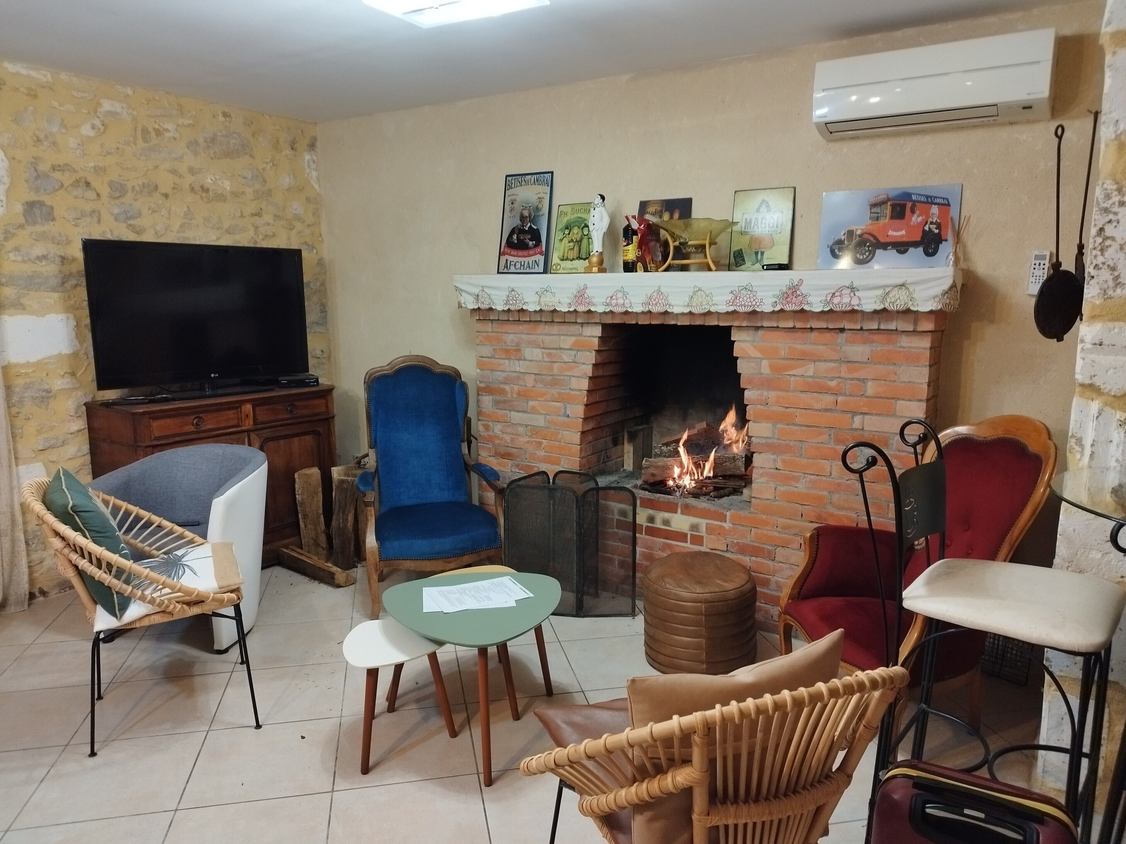 Un soggiorno con televisione, camino, poltrone in vimini e un tavolo.