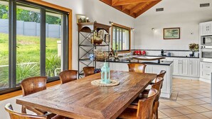 Une cuisine spacieuse avec une table à manger en bois, des placards blancs et une vue sur le jardin.