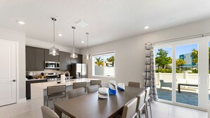 A modern kitchen with a dining area, large windows, and a view of the outdoors.